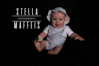 Smiling baby in a matching hat outfit holding a chew giraffe.