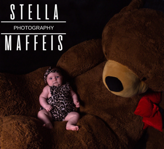 Baby lying on a giant teddy bears lap.