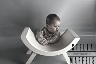 A baby sitting on a little white bench.