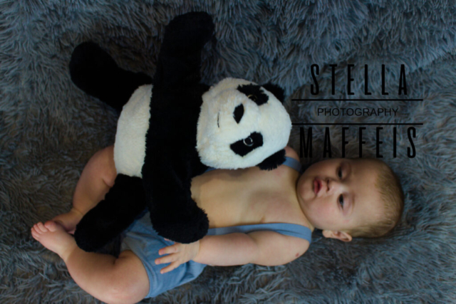 A baby holding a panda teddy.
