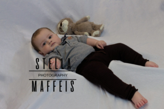 Baby lying with a sloth teddy.