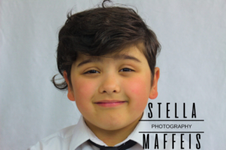 A smiling boy in a tie and white shirt.