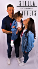 A curly, smiling toddler being held by her dad while her mommy tries to kiss her cheek.