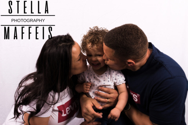 Mother and father kissing their toddlers cheeks.