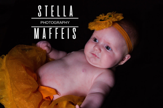 Baby in an orange tutu and halloween headband.